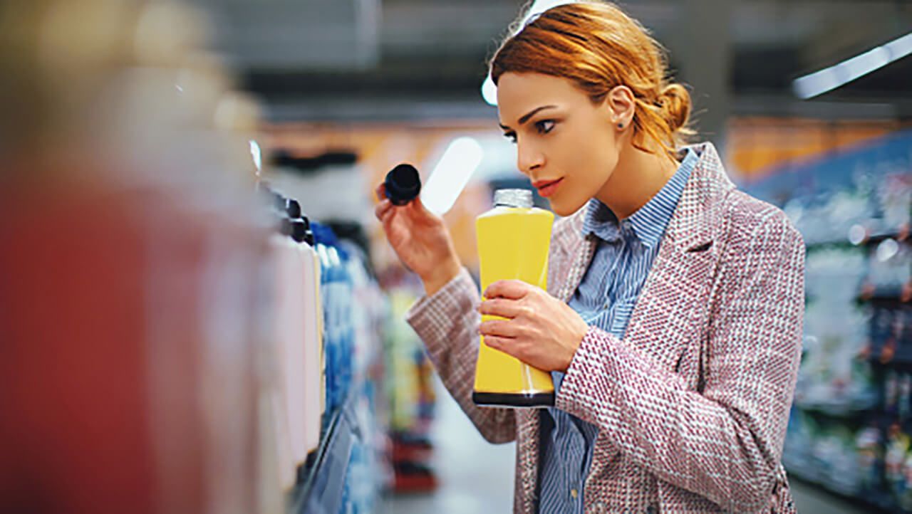 A lady in a shop smells the fragrance of a product having taken the lid off.