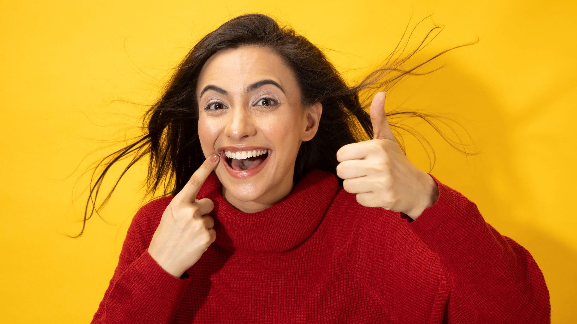 A smiling girl wearing a maroon coloured t-shirt.
