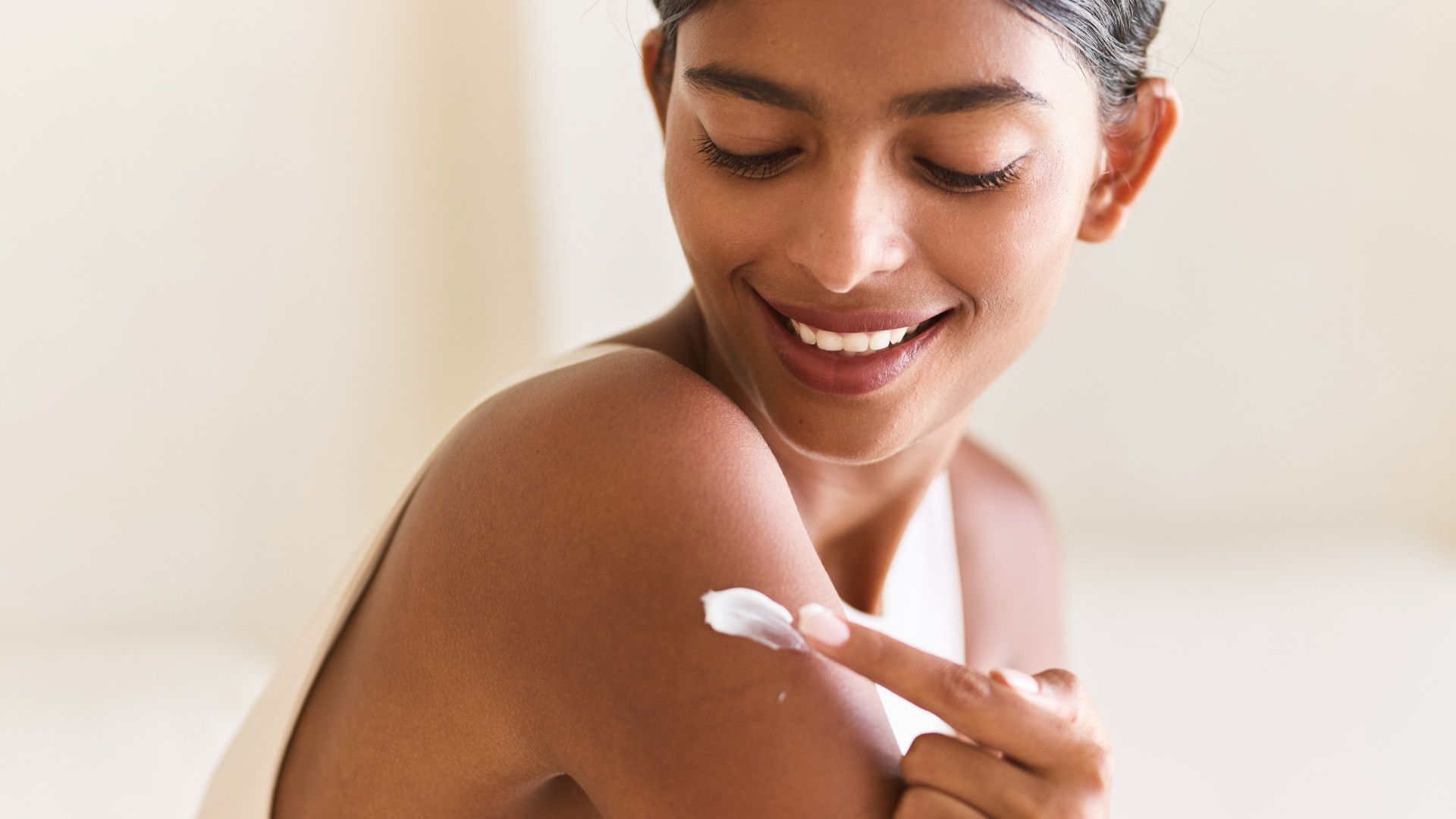 A woman putting lotion on her arm
