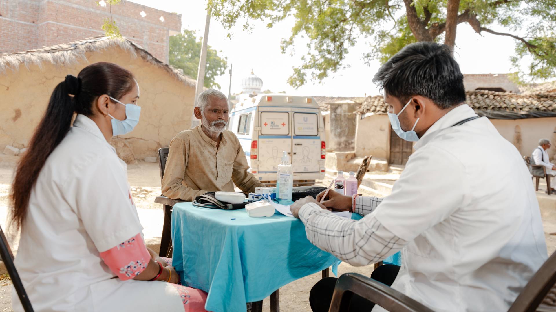 Outdoor medical consultation with masks and equipment.