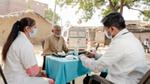 Outdoor medical consultation with masks and equipment.