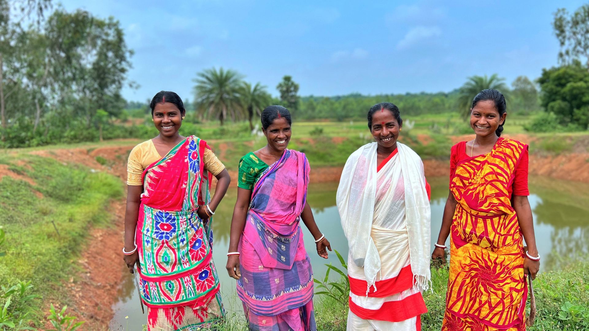 A picture if happy women farmers alongside a water pond