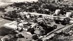 Aerial view of an industrial building complex surrounded by trees and roads in a rural area.
