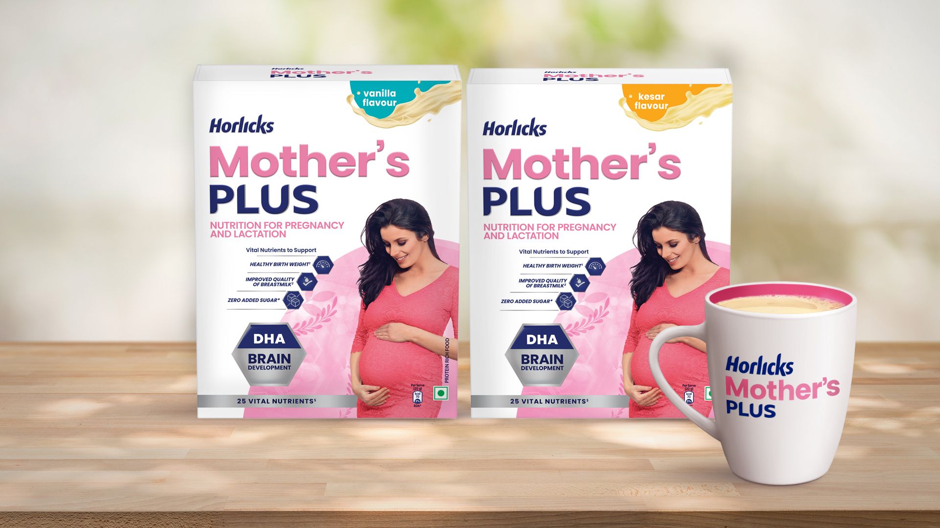Two packs of Horlicks Mother's Plus nutrition drink in vanilla and kesar flavours featuring a pregnant woman in a pink dress, along with a filled mug displayed on a wooden surface.