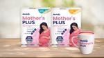 Two packs of Horlicks Mother's Plus nutrition drink in vanilla and kesar flavours featuring a pregnant woman in a pink dress, along with a filled mug displayed on a wooden surface.