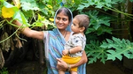 A woman carrying a baby while showing trees