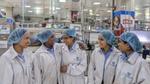 A group of women working at HUL's factory. They are wearing white coats and their hair is covered with a cap.
