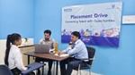 Three people in a room with a laptop and documents on the table, under a banner reading "Placement Drive".