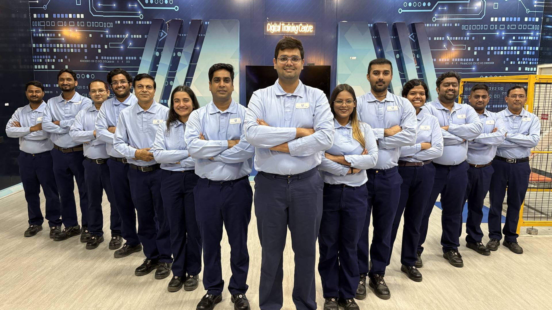14 employees from Unilever’s Tinsukia Beauty & Wellbeing factory in India, a WEF Lighthouse Network site. They are wearing light blue shirts, standing and smiling at the camera.   