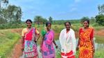 Four women are standing in front of a body of water