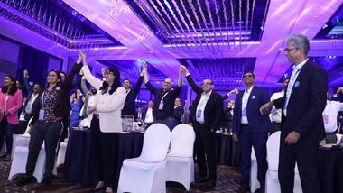 A group of conference attendees raise their hands in enthusiasm.