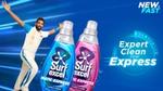An athlete in uniform joyfully poses with two Surf excel Matic Express detergent bottles. On the right the text reads "Expert Clean now Express".