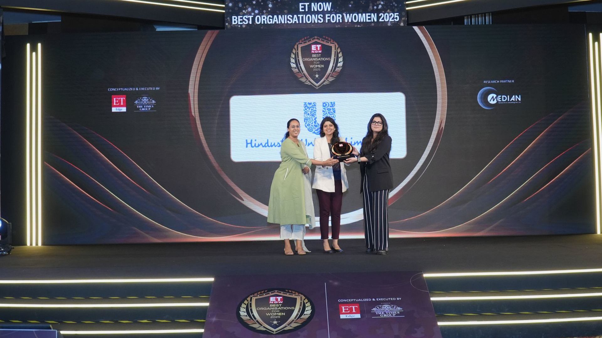 Three women on stage with the Best Organisations for Women 2025 award.