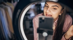 Woman filming herself with a smartphone and ring light