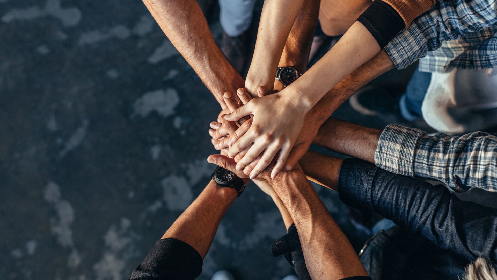 People placing their hands on top of each other signifying collaboration