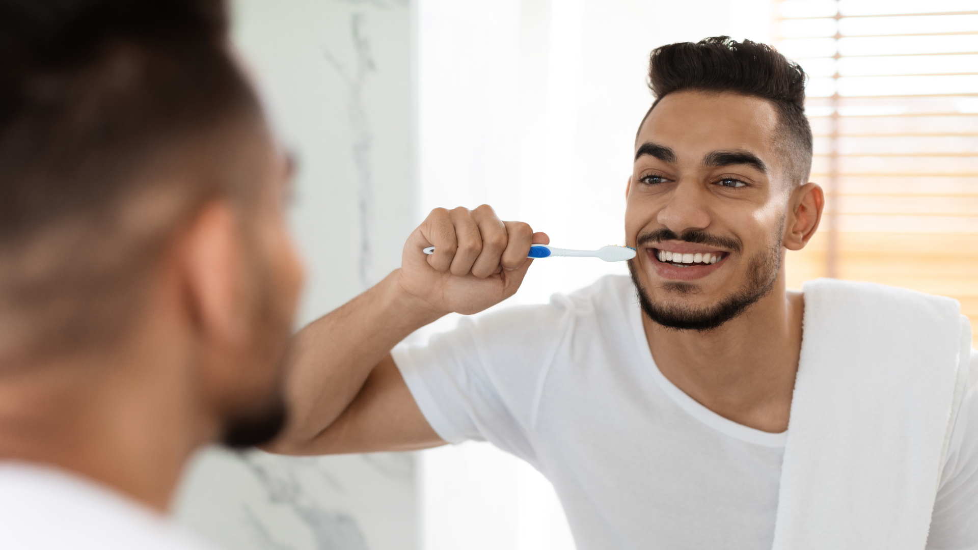 A man in white shirt brushing his teeth.
