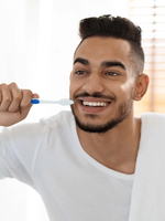 A man in white shirt brushing his teeth.