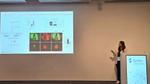 Scientist presents cancer research data on a large screen at a SynSci conference podium.