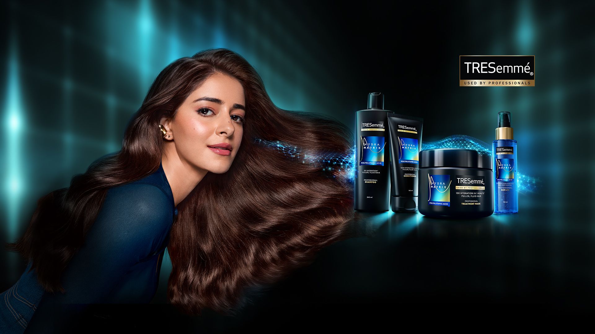 Woman with long, glossy hair posing beside TRESemmé Hydra Matrix hair care products on a dark, glowing background.