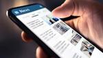 A close up of someone holding a mobile phone and scrolling through articles in a newsfeed