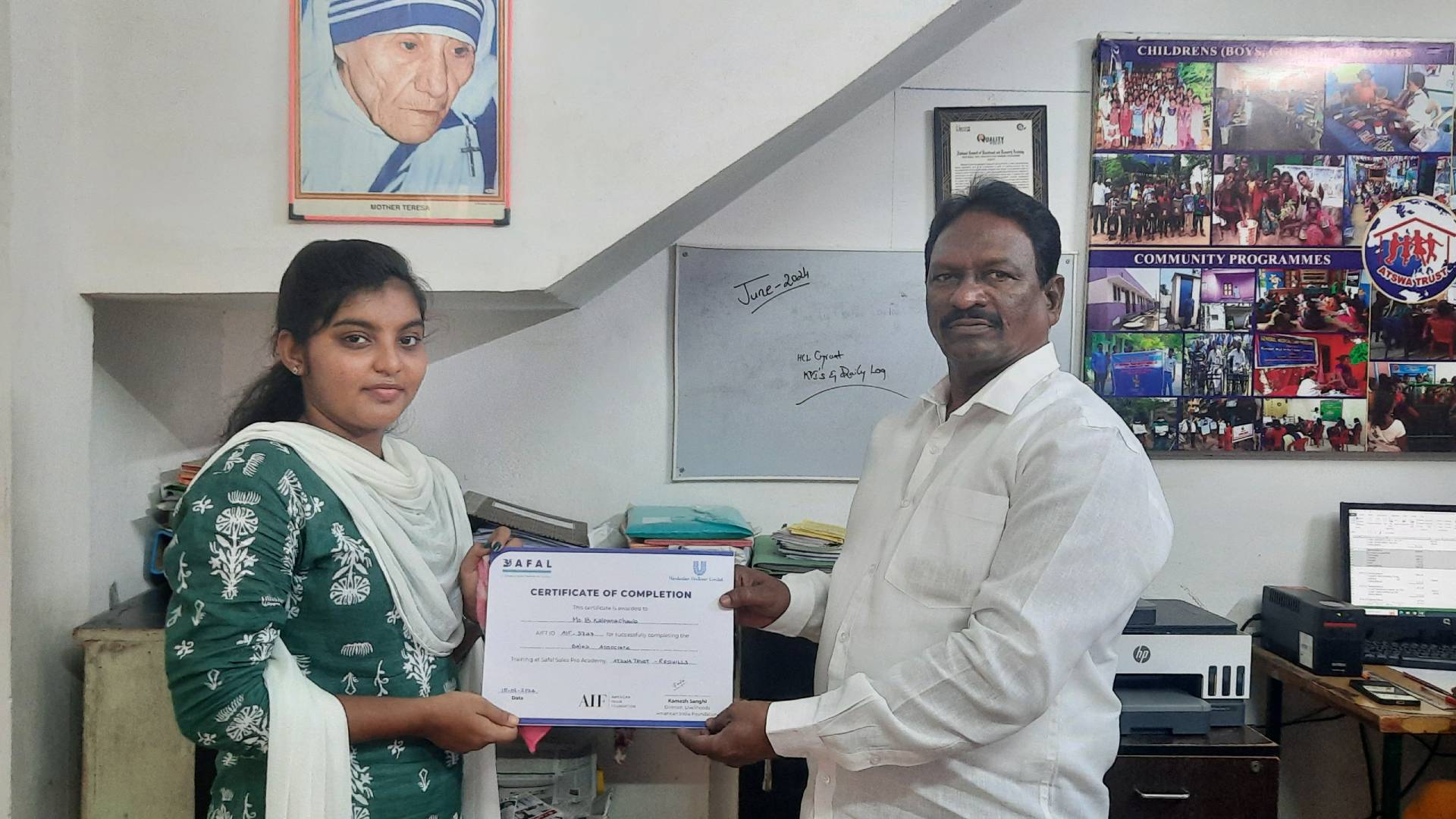 Two people holding a certificate in an office setting.