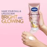 Hand applying Vaseline Gluta-Hya Dewy Radiance serum-in-lotion against a pink background with bright skin tagline