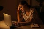 A picture of a lady in front of her laptop working in a dim light set up
