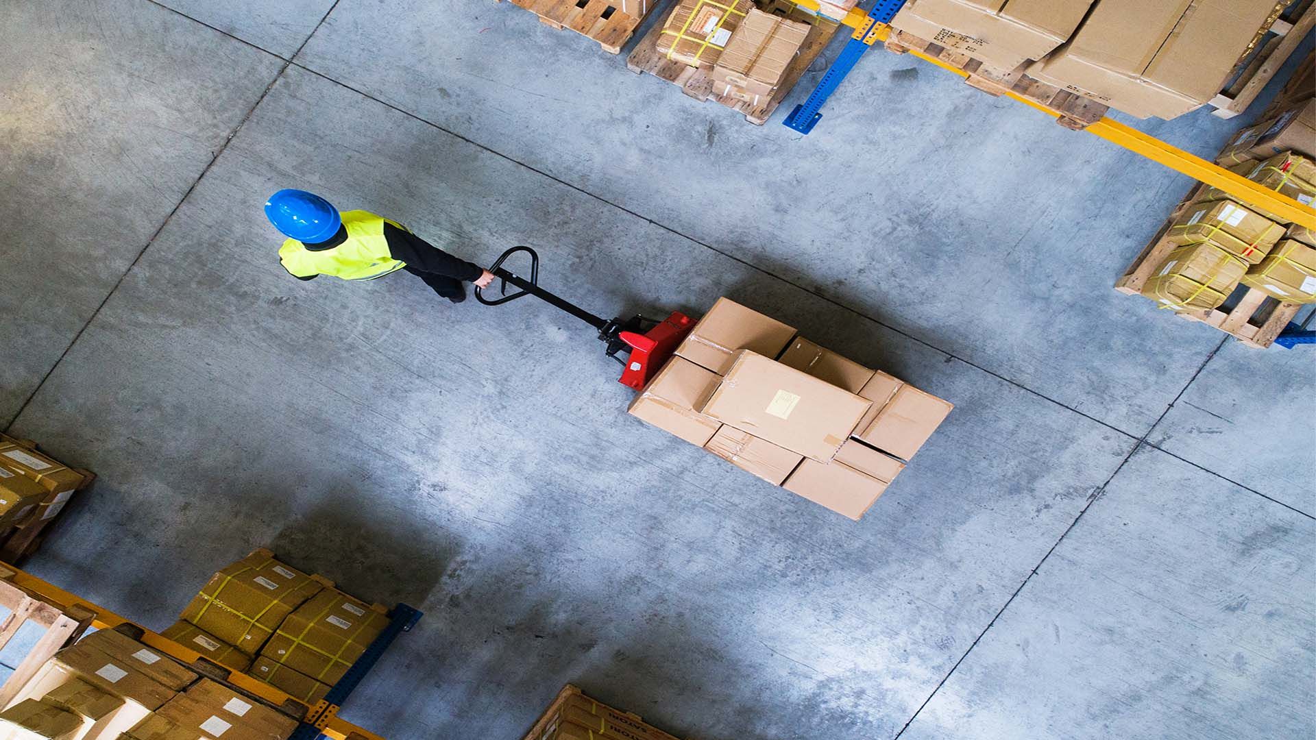 An aerial view of a man pulling a trolley through a warehouse loading bay