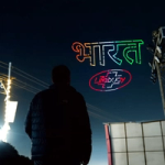 Silhouette of a person looking at a night sky with colorful drone lights forming text and the Lifebuoy logo.