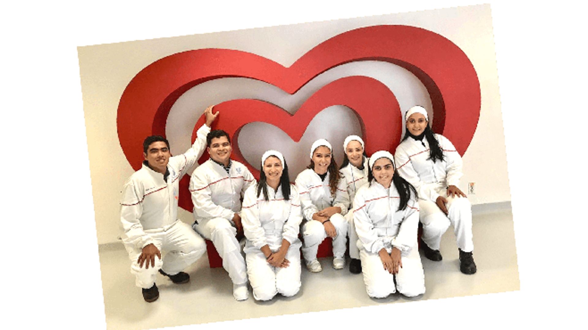 An image of happy HUL employees posing for a picture in front of a heart shaped structure. 