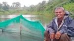 A man sitting beside a rainwater storage pond and a harvesting pit.