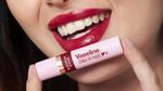 Smiling woman with red lips holding a Vaseline Emily in Paris Rouge Romance moisturizing lip balm