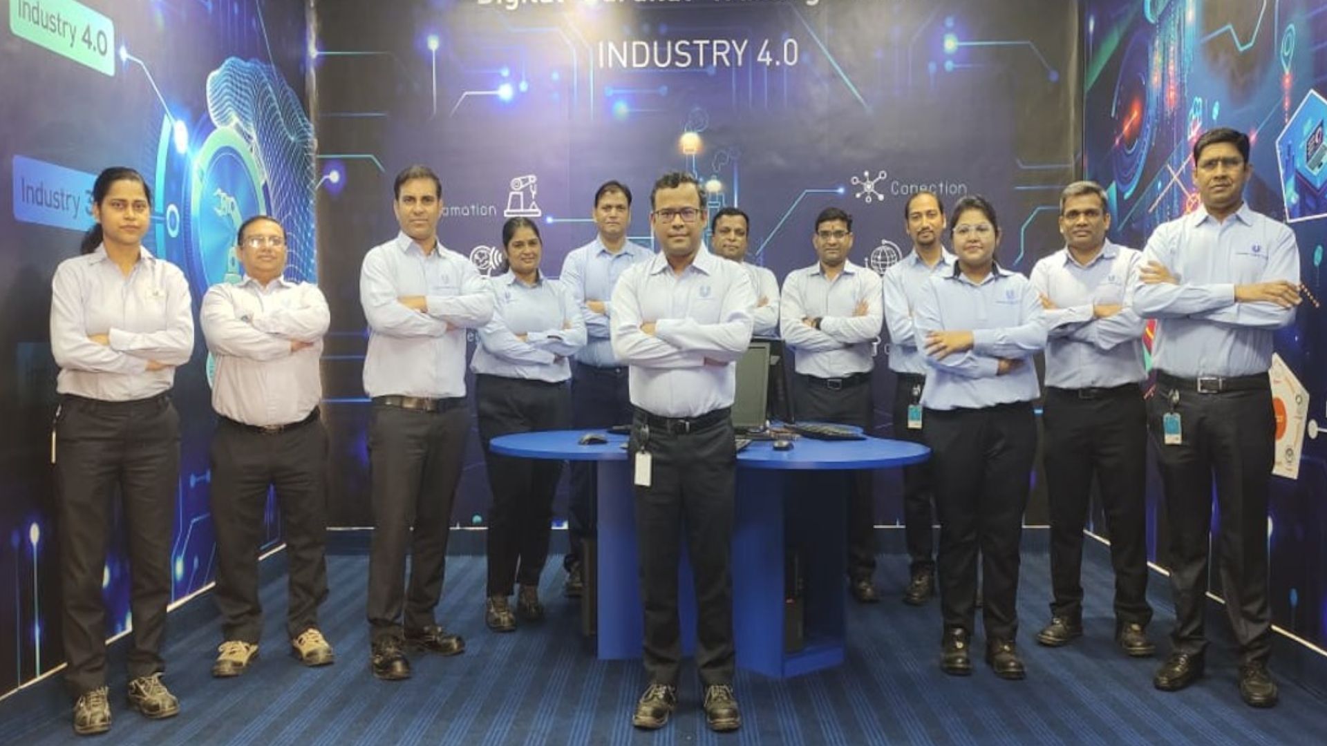 Image of 12 members of the Sonepat factory team standing in front of a blue Industry 4.0 background