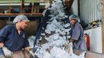 Two women workers sorting recyclable plastic waste on a conveyor belt at a recycling plant.