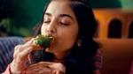 Person in a cozy sweater having a bite. Kissan logo in the top left corner.