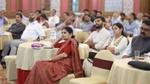 A group of attentive participants seated at tables during a seminar in a spacious, well-decorated room.
