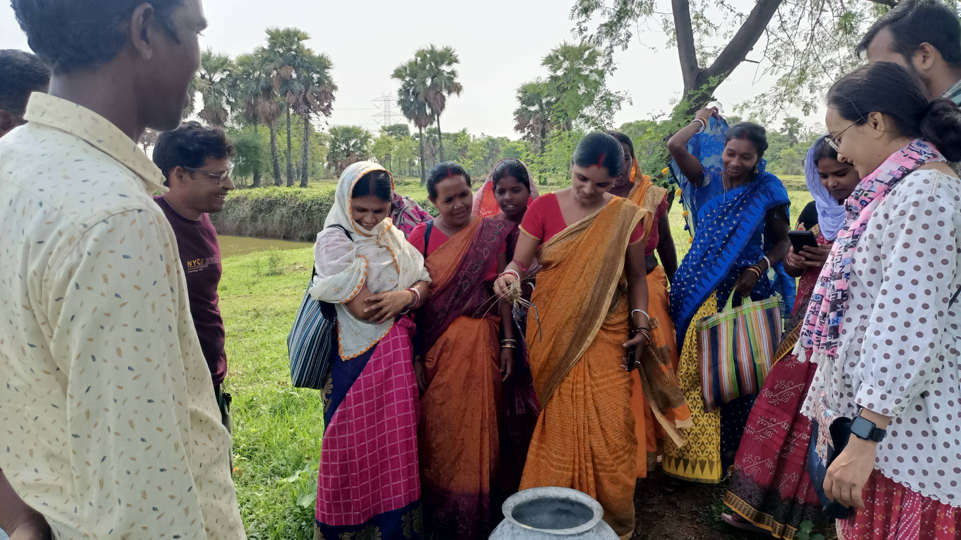 a group of people standing outside, with a woman wearing a sari