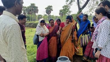 a group of people standing outside, with a woman wearing a sari