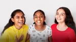 An image of three young girls standing together and laughing.
