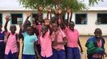Smiling children in pink and blue shirts show their clean hands to the camera.