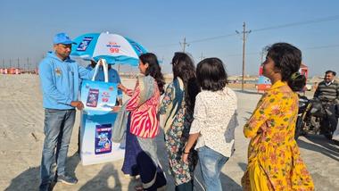 A man handing over a Surf excel easy bag to a group of women.